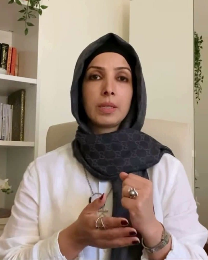 نائلة السقاف تتحدث إلى الكاميرا في مكتبها أمام مكتبة كتب